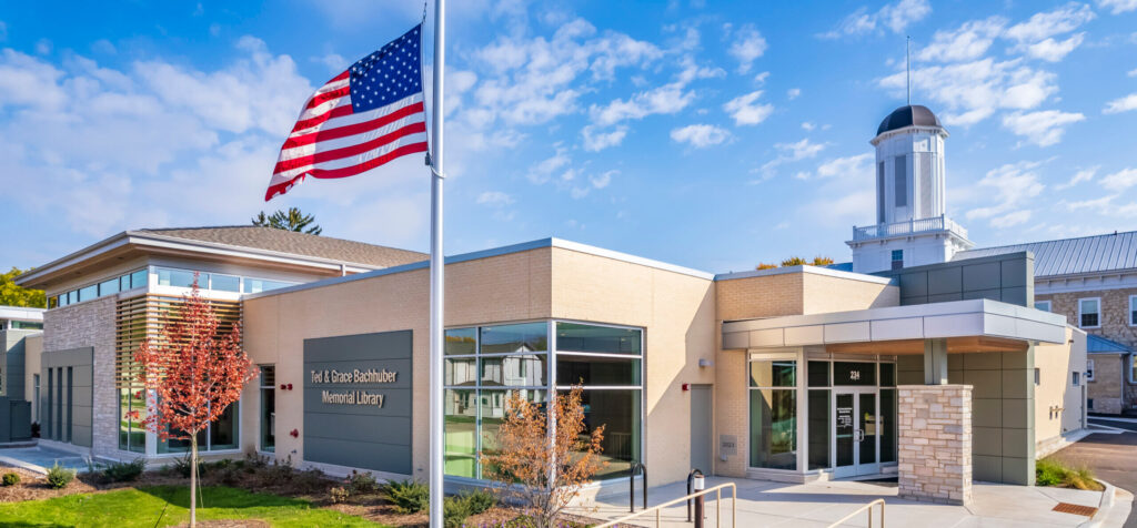 A picture of the library with an American flag blowing in the wind